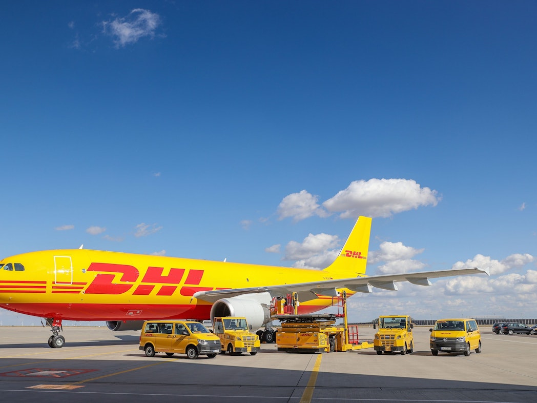 Ein Frachtflugzeug von DHL und verschiedene Fahrzeuge für die Logistik stehen in unserem Archivbild von 2020 auf dem Vorfeld auf dem Flughafen Leipzig/Halle. Der Logistikriese Deutsche Post DHL verschickt bis auf Weiteres keine Express-Sendungen und kein Frachtgut mehr nach Russland.