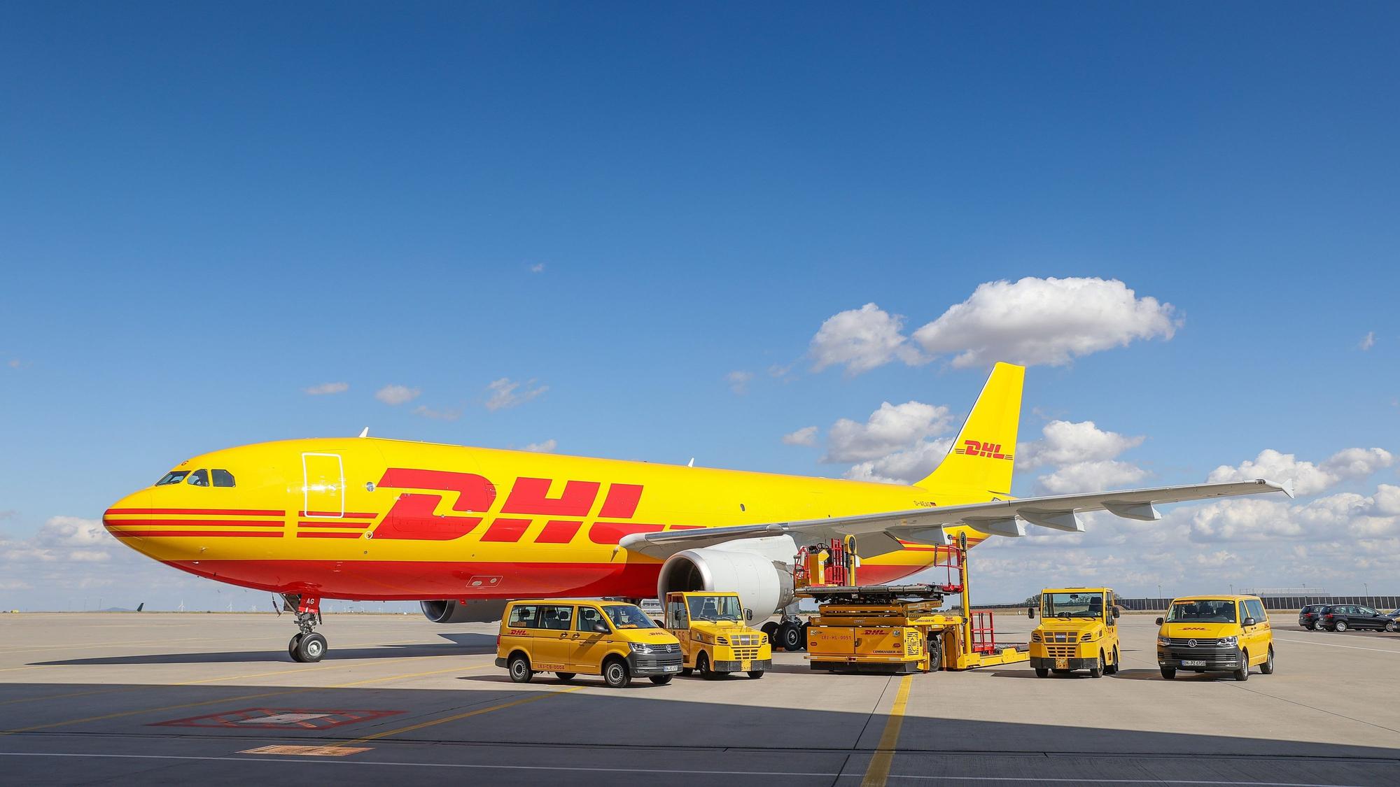 Ein Frachtflugzeug von DHL und verschiedene Fahrzeuge für die Logistik stehen in unserem Archivbild von 2020 auf dem Vorfeld auf dem Flughafen Leipzig/Halle. Der Logistikriese Deutsche Post DHL verschickt bis auf Weiteres keine Express-Sendungen und kein Frachtgut mehr nach Russland.