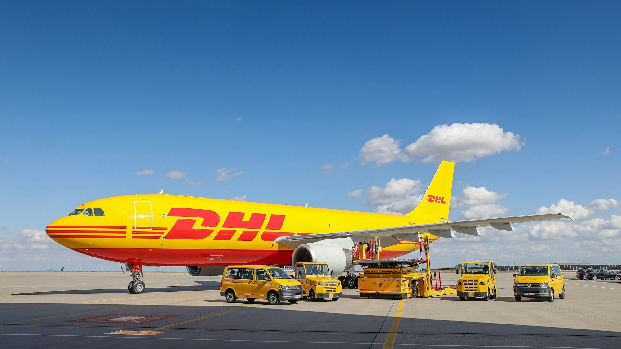 Ein Frachtflugzeug von DHL und verschiedene Fahrzeuge für die Logistik stehen in unserem Archivbild von 2020 auf dem Vorfeld auf dem Flughafen Leipzig/Halle. Der Logistikriese Deutsche Post DHL verschickt bis auf Weiteres keine Express-Sendungen und kein Frachtgut mehr nach Russland.