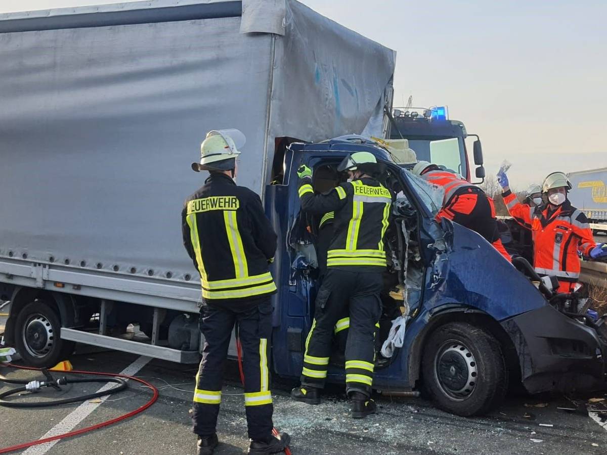 Feuerwehrleute kümmern sich um den Fahrer eines völlig zerstörten Kleinlasters auf der A3 bei Königswinter.
