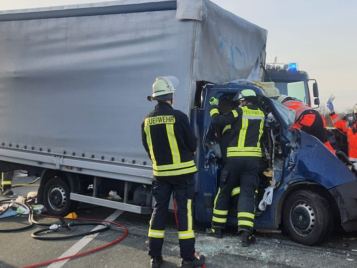 Feuerwehrleute kümmern sich um den Fahrer eines völlig zerstörten Kleinlasters auf der A3 bei Königswinter.