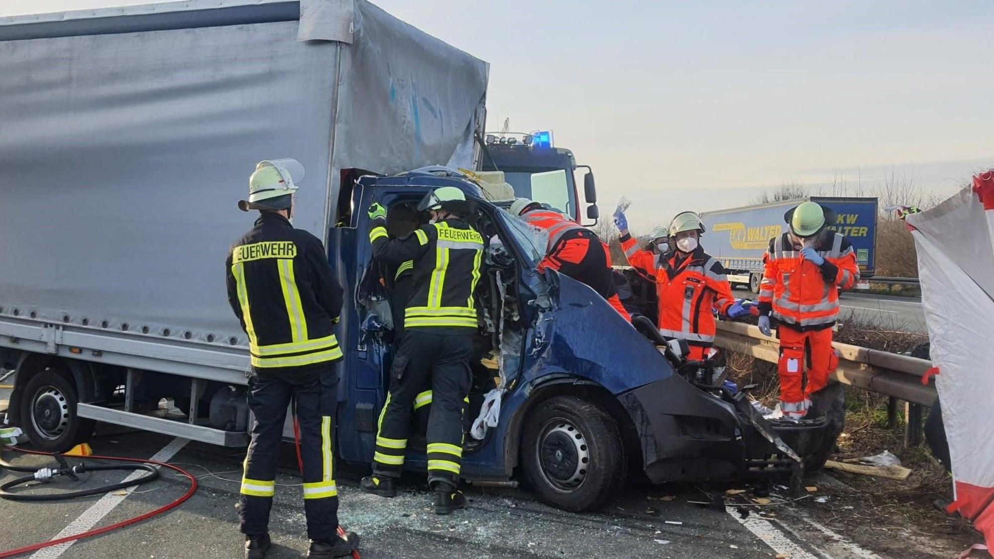 Feuerwehrleute kümmern sich um den Fahrer eines völlig zerstörten Kleinlasters auf der A3 bei Königswinter.