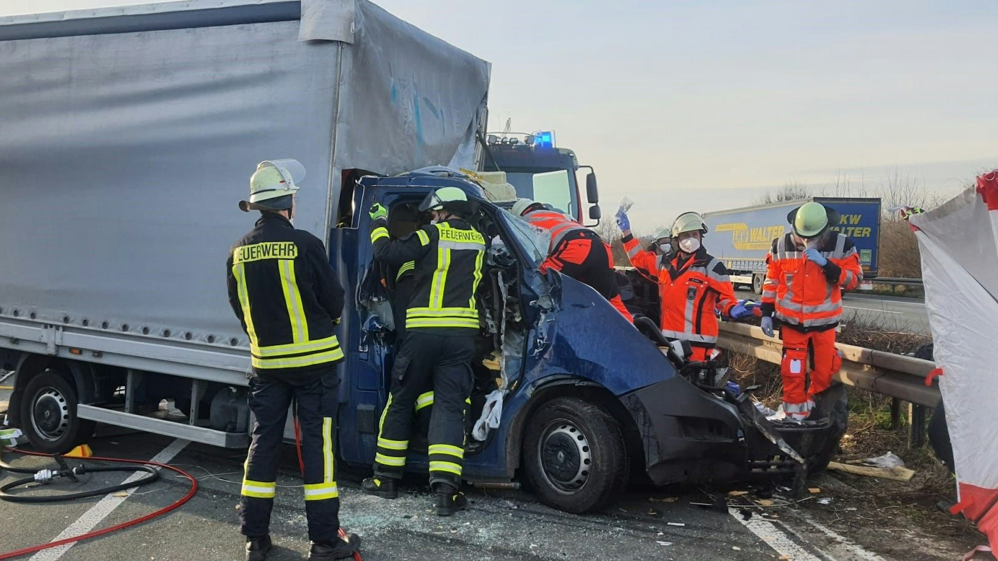 Feuerwehrleute kümmern sich um den Fahrer eines völlig zerstörten Kleinlasters auf der A3 bei Königswinter.