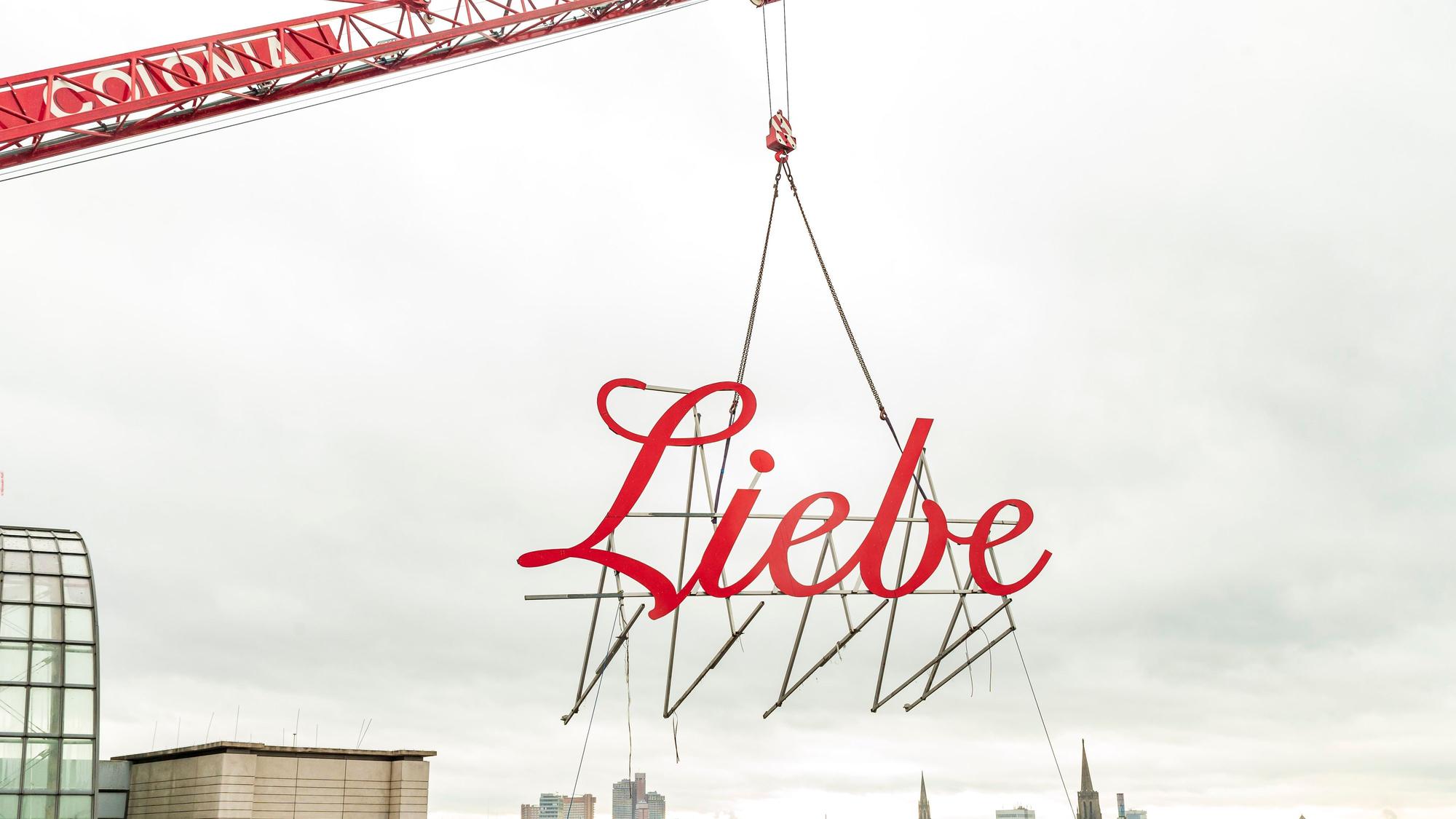 Schriftzug Liebe wird mit einem Kran vom Gebäude geholt.