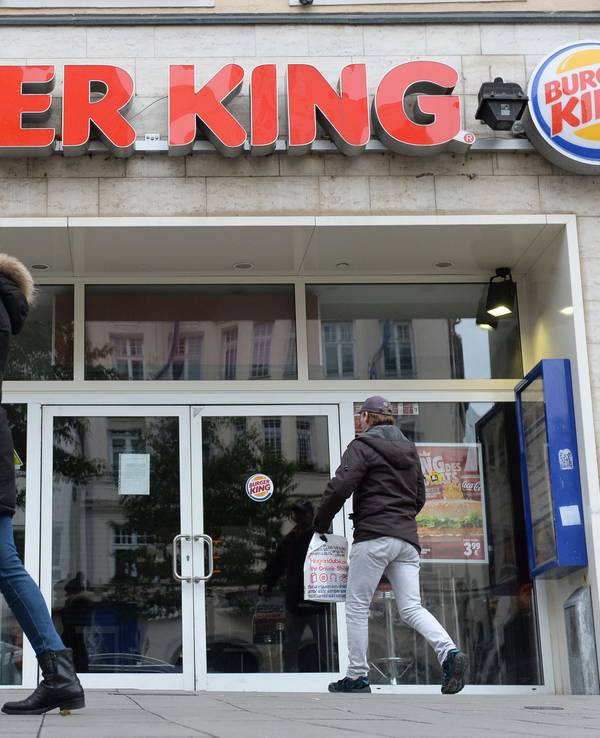 Menschen gehen an Filiale von Burger King vorbei.