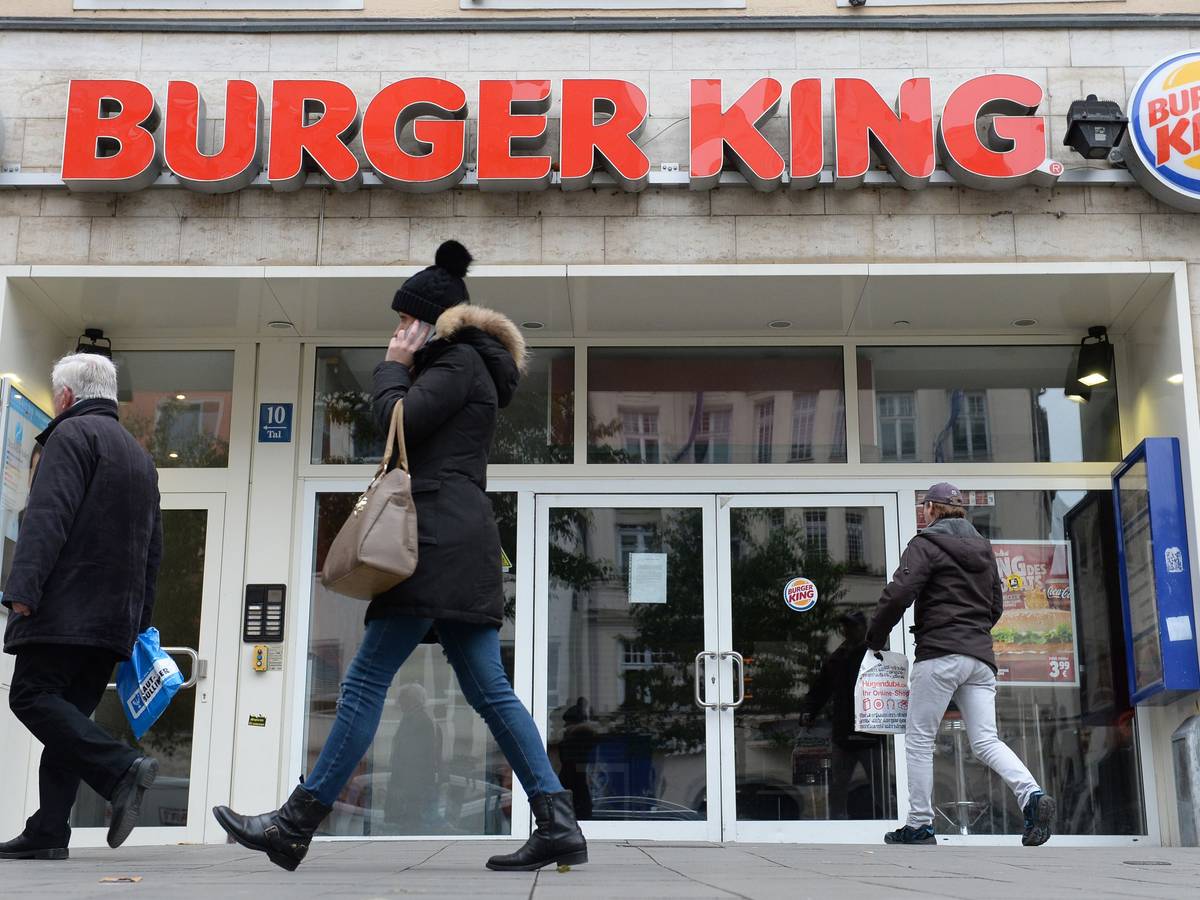Menschen gehen an Filiale von Burger King vorbei.