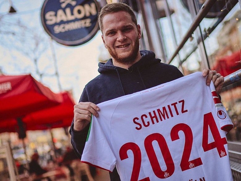 Benno Schmitz präsentiert zur Unterschrift seines neuen Vetrages ein Trikot mit der Aufschrift „Schmitz 2024“