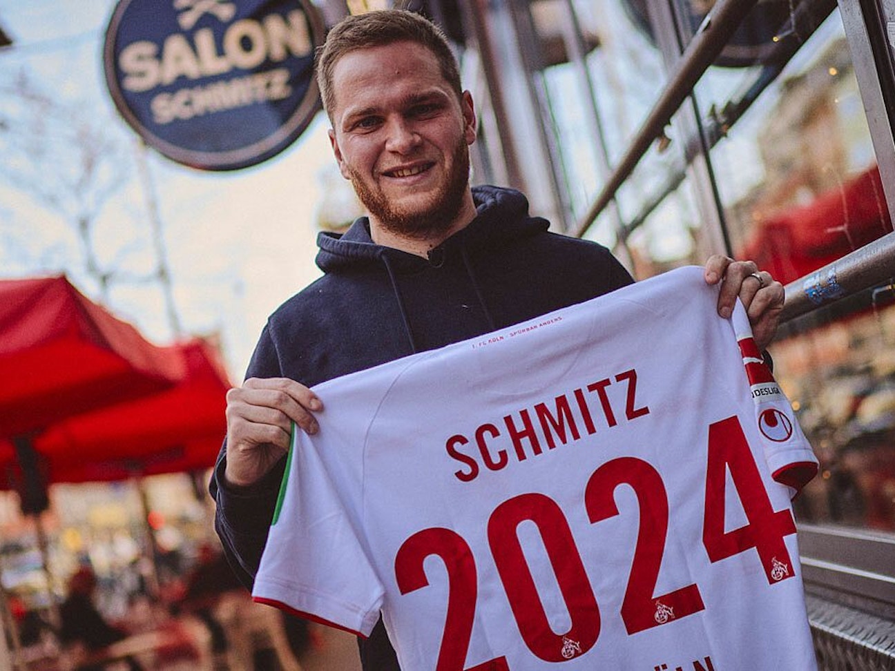 Benno Schmitz präsentiert zur Unterschrift seines neuen Vetrages ein Trikot mit der Aufschrift „Schmitz 2024“