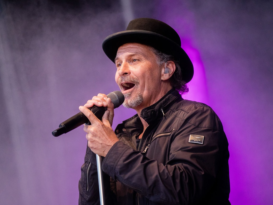 Sänger Peter Brings steht mit Mikro auf der Bühne und singt.