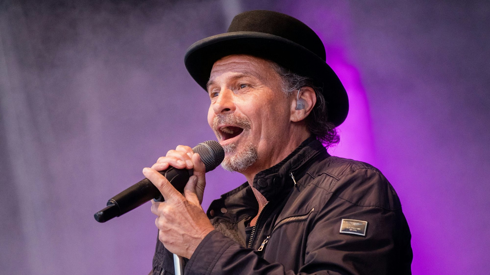 Sänger Peter Brings steht mit Mikro auf der Bühne und singt.