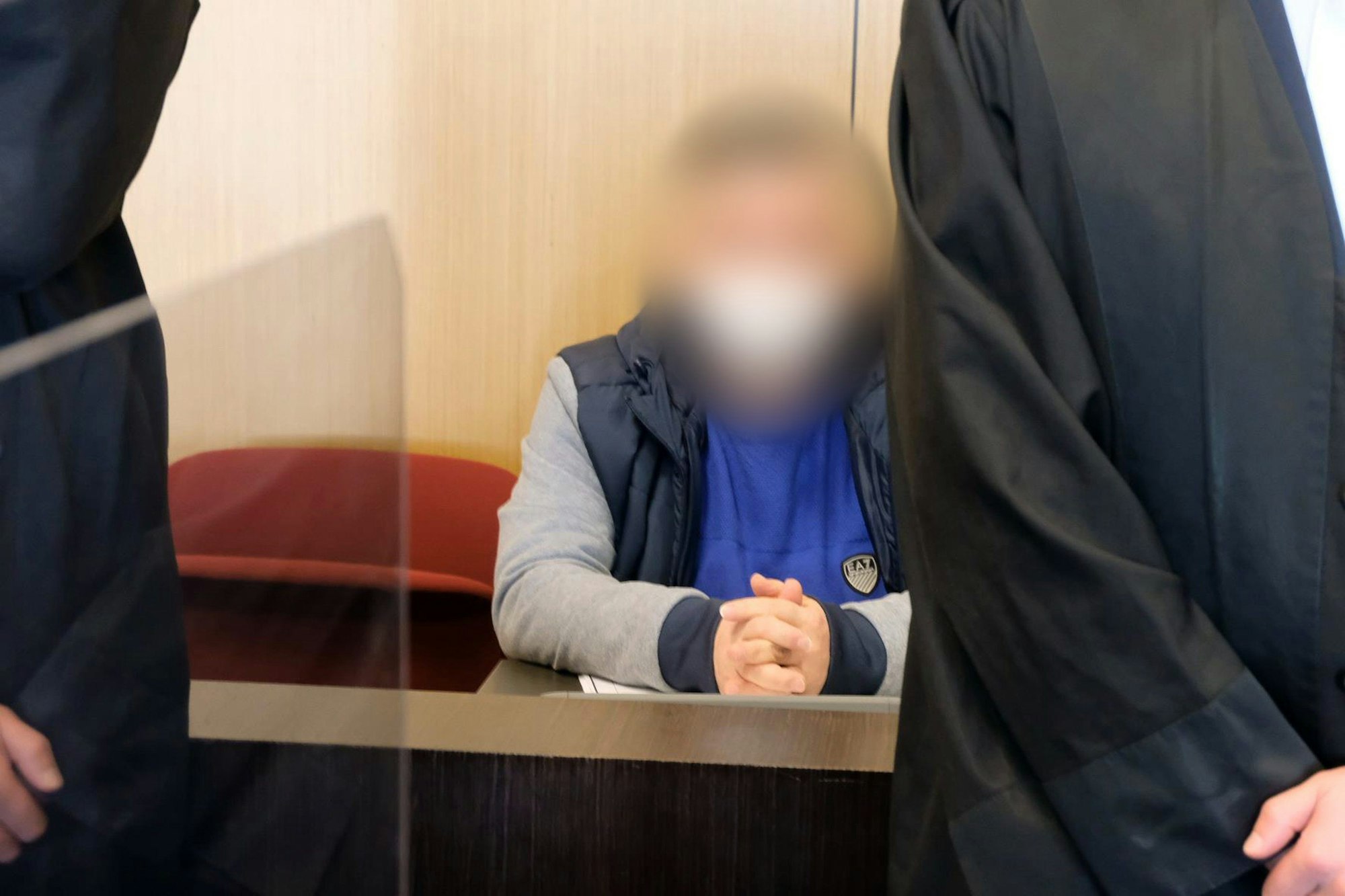 Ein Angeklagter sitzt flankiert von seinen Anwälten auf der Anklagebank des Landgerichts Düsseldorf.