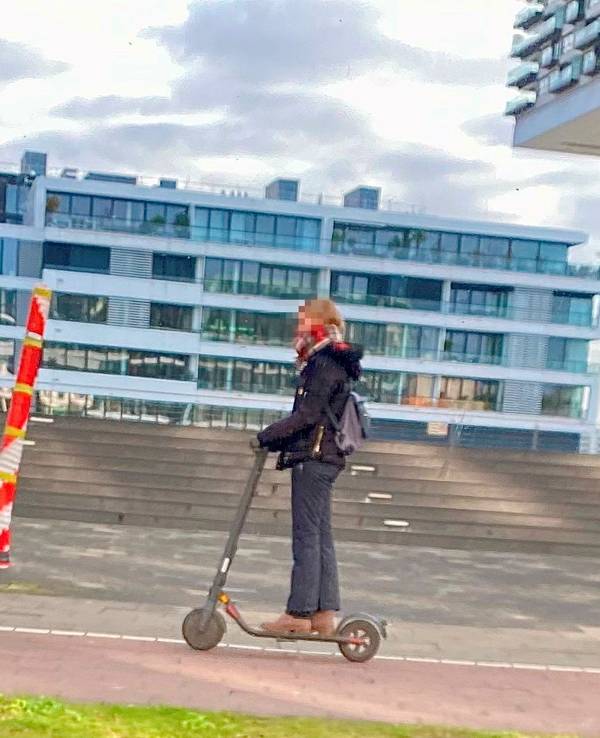 Ein Mast mitten auf dem Gehweg am Rheinauhafen in Köln, fotografiert vor wenigen Tagen. Eine Person fährt mit einem Roller daran vorbei.