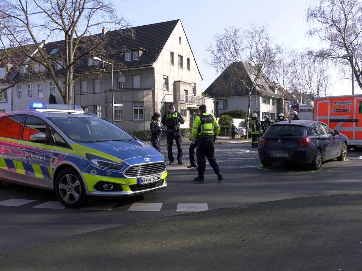 Polizisten stehen nach einem Unfall auf einer Straße in Köln.