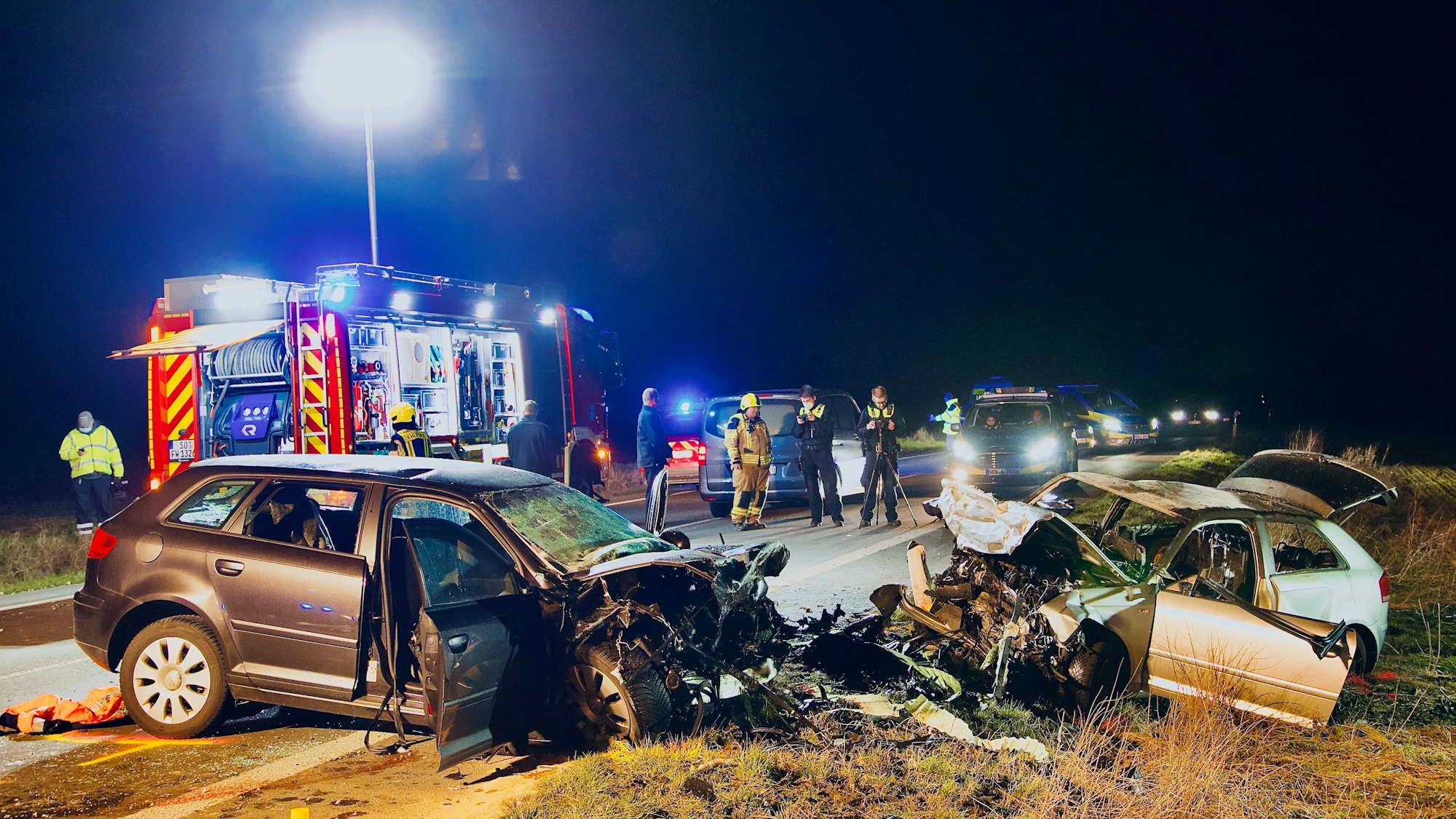 Einsatzkräfte der Polizei und Feuerwehr stehen an der Unfallstelle. Bei einem Frontalzusammenstoß in Unna sind am Samstag (5. März 2022) drei Menschen gestorben.