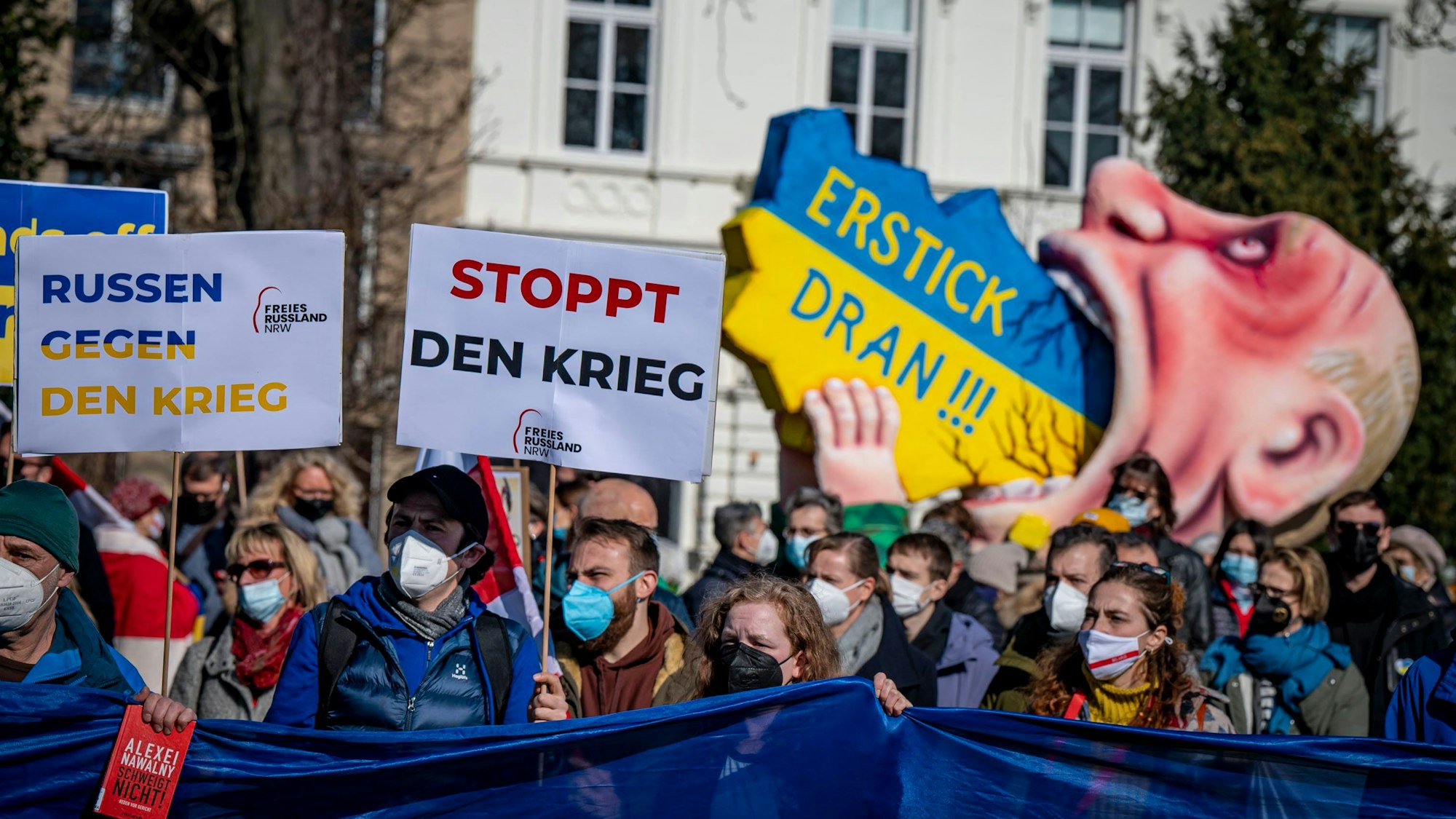 Menschen halten Plakate bei einer Demo hoch.