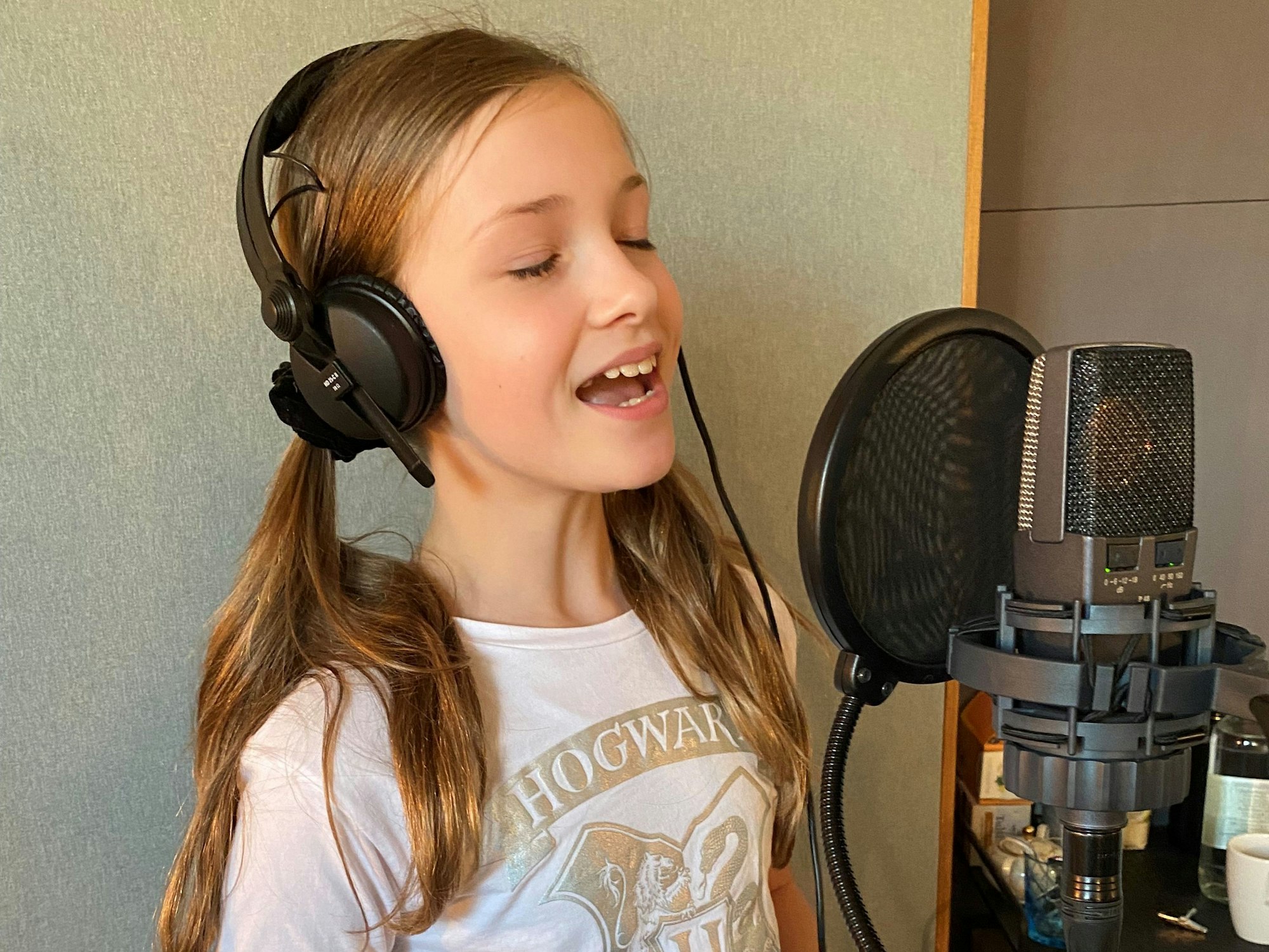 Ein Mädchen steht in einem Tonstudio vor einem Mikrofon