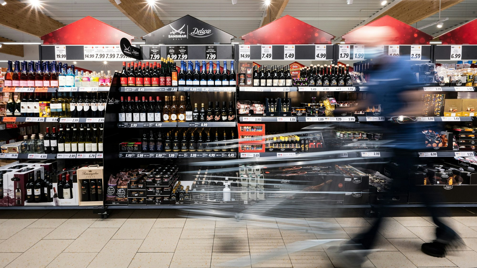 Ein Mann geht in unserem Archivbild vom Dezember 2021 mit seinem Einkaufswagen in einer Lidl-Filiale an Regalen vorbei. Egal ob  Nudeln, Brot oder Kaffee: Vieles ist bereits jetzt teurer als noch vor einigen Monaten. Durch den Ukraine-Krieg könnte sich die Preisspirale bald sogar noch schneller drehen.