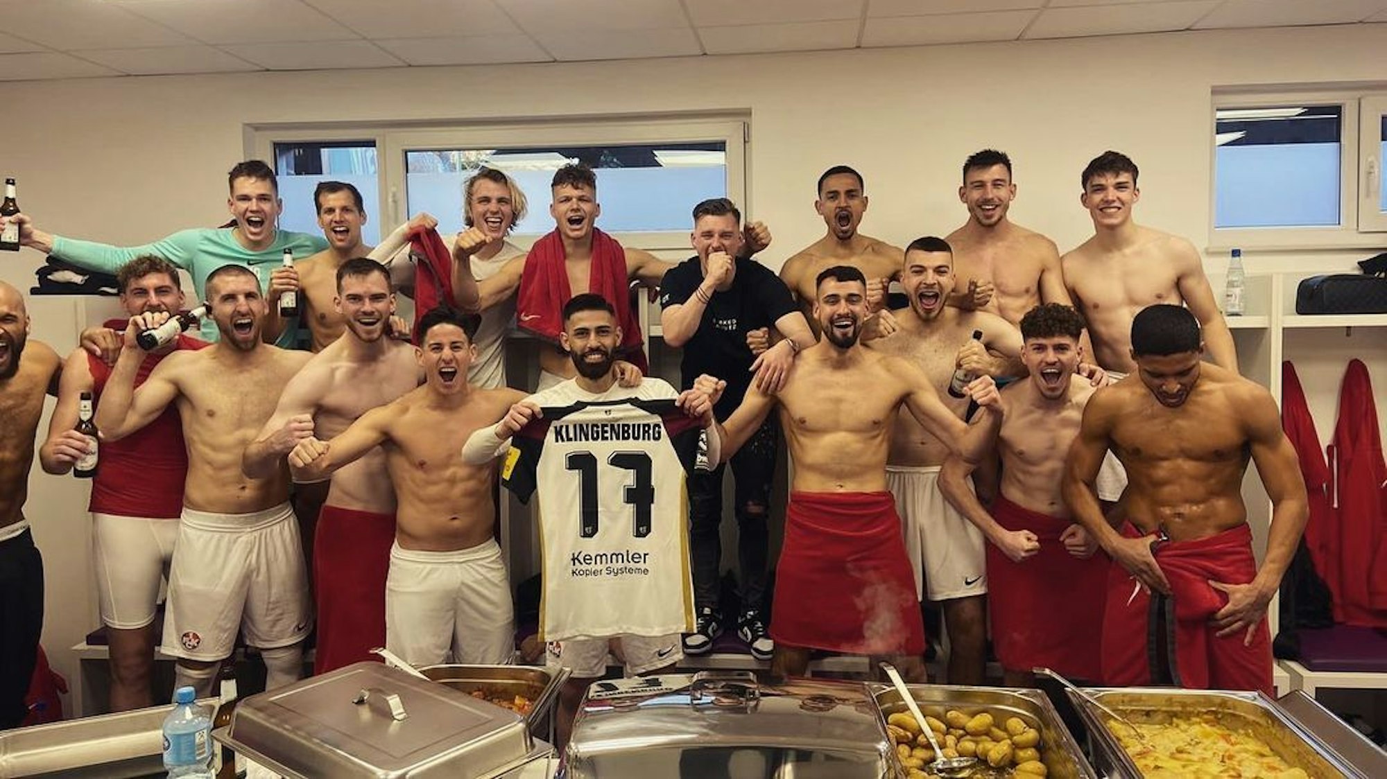 Die Mannschaft des 1. FC Kaiserslautern feiert den Sieg beim VfL Osnabrück in der Kabine und posiert mit einem Trikot des verletzten Teamkollegen René Klingenburg.