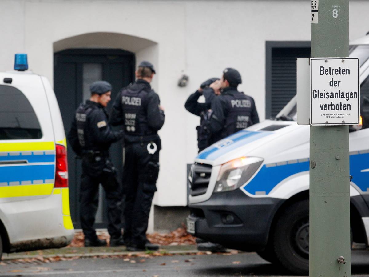 Polizisten stehen vor einem Haus.
