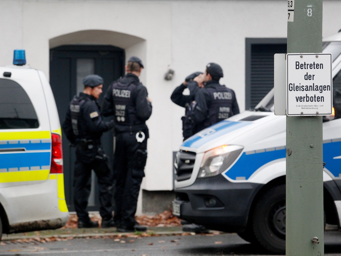 Polizisten stehen vor einem Haus.