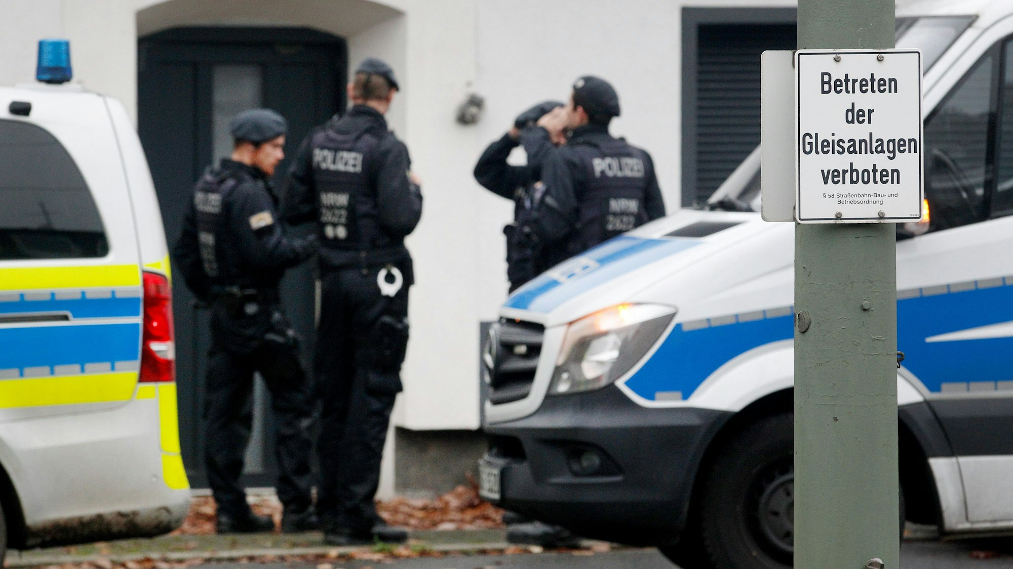 Polizisten stehen vor einem Haus.