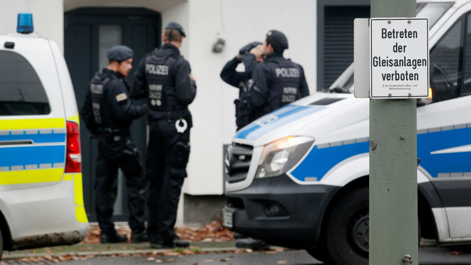 Polizisten stehen bei einer Razzia vor einem Haus.