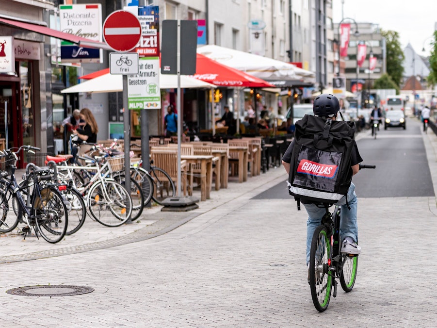 Ein Fahrer des Lieferdienstes Gorillas ist am 20. August 2021 in der Kölner Südstadt unterwegs. In diesem Fall entgegengesetzt der Einbahnstraße, aber das Schild weist darauf hin, dass es erlaubt ist.
