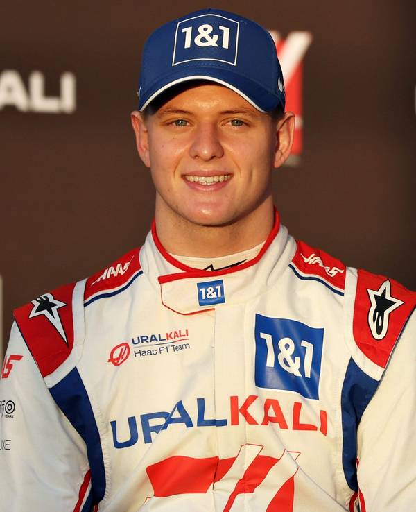 Mick Schumacher steht bei einem Foto-Shooting der Formel 1 vor einer Werbe-Wand.