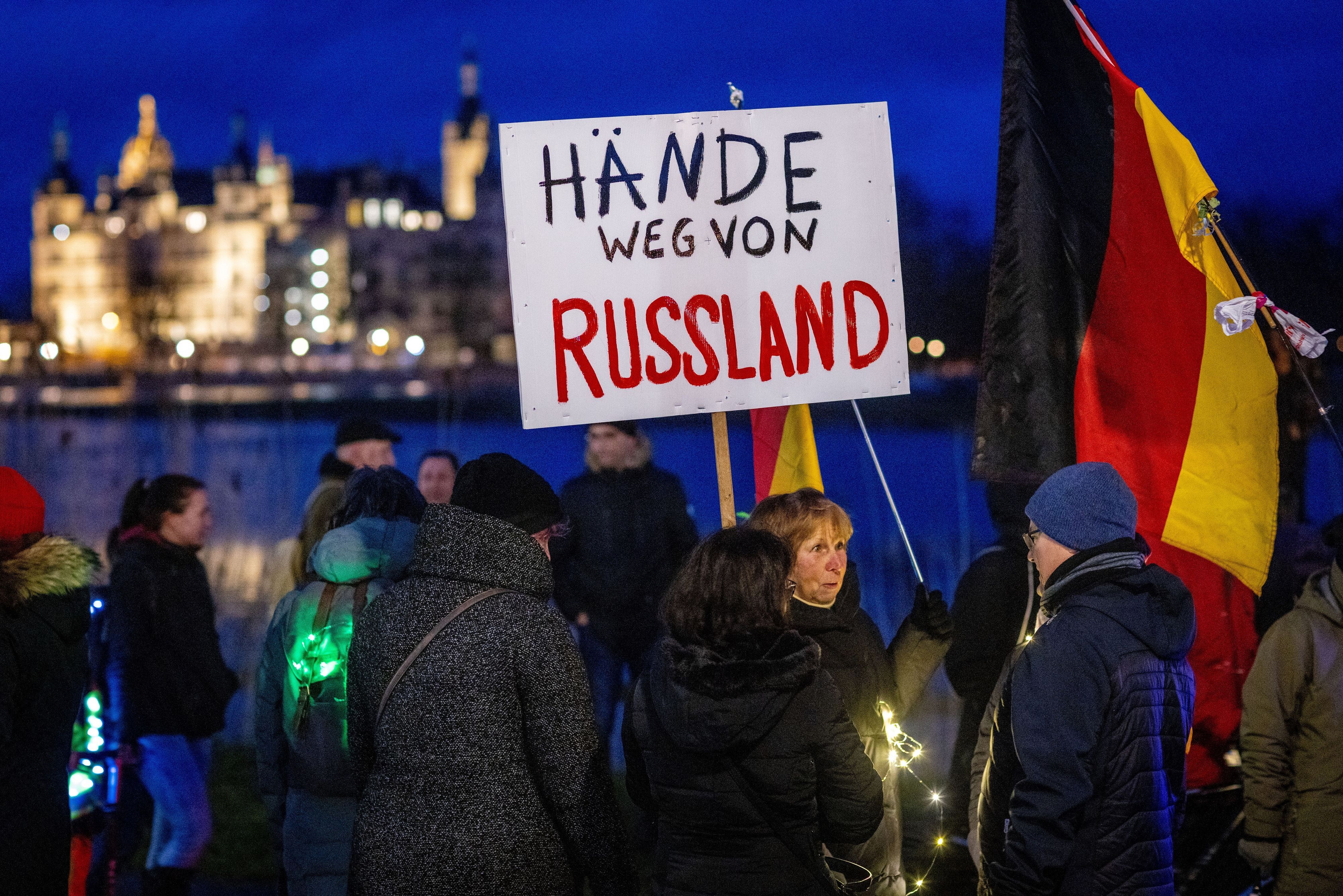 Teilnehmer einer Protestaktion gegen die Corona-Schutzmaßnahmen (Februar 2022) halten ein Schild mit der Aufschrift „Hände weg von Russland“.