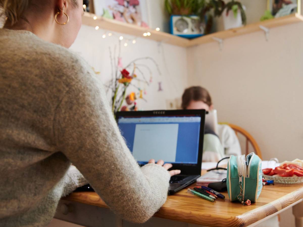 Eine Frau arbeitet am Küchentisch an ihrem Laptop.