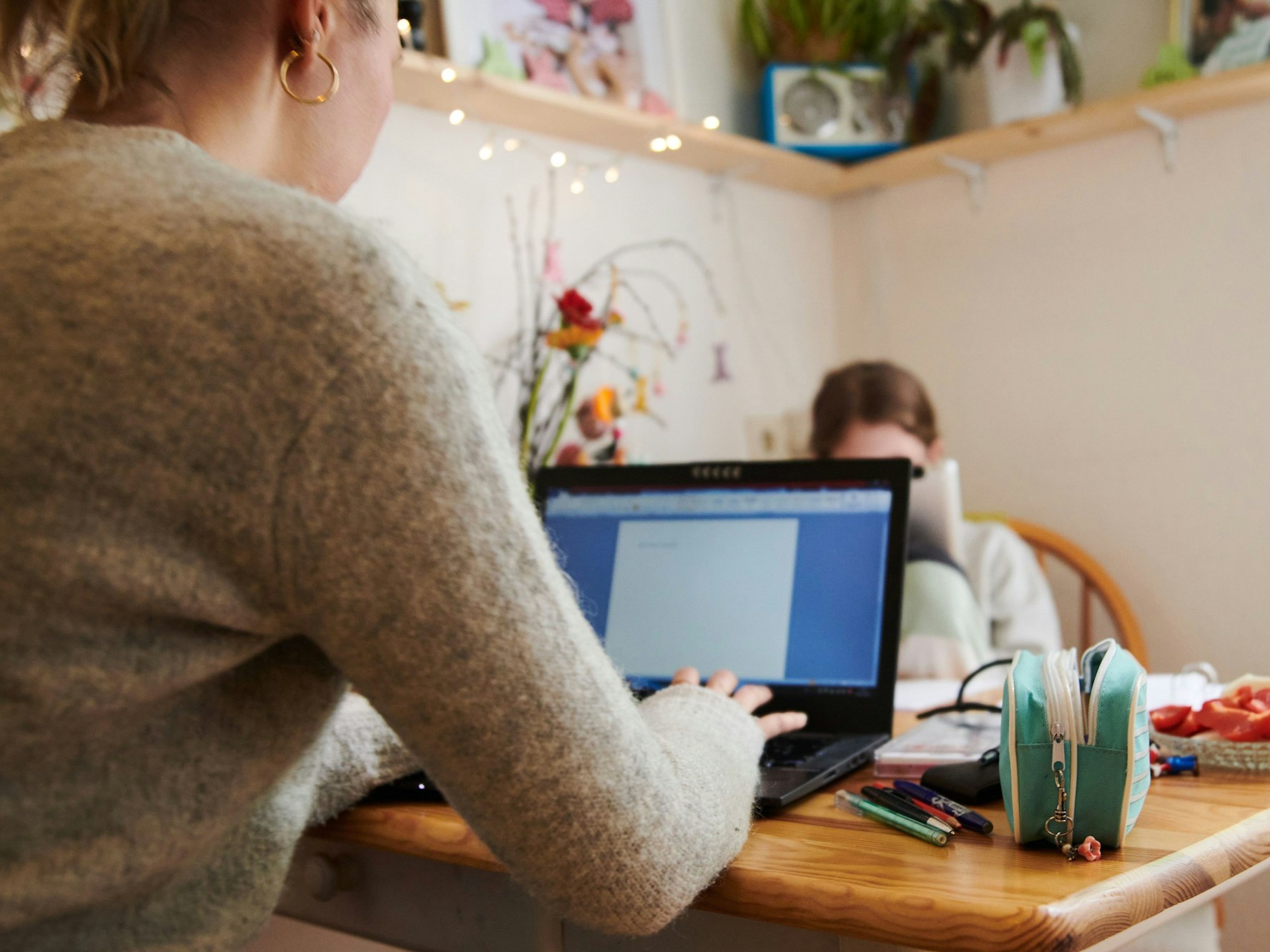 Eine Frau arbeitet am Küchentisch an ihrem Laptop.