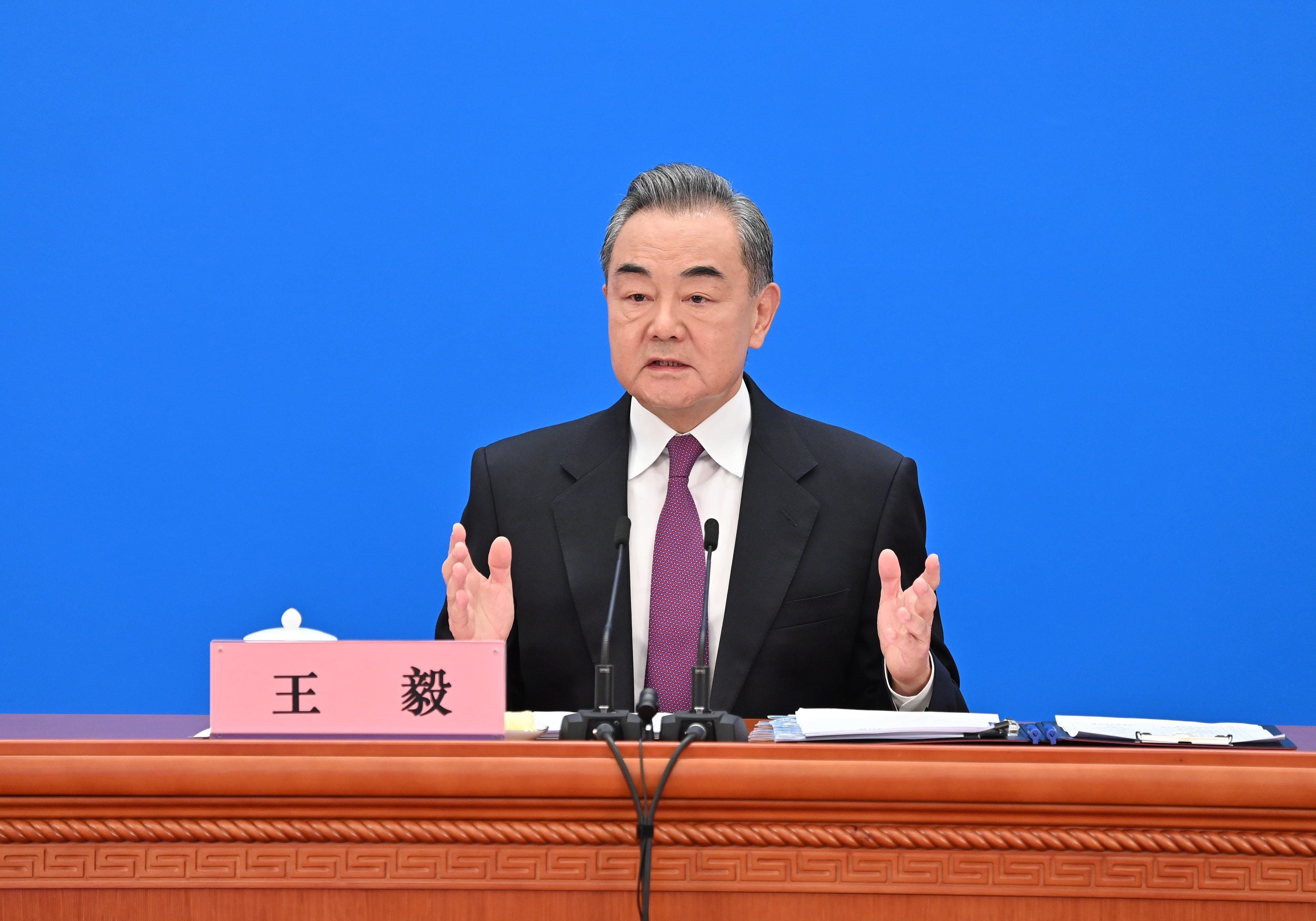 Chinas Außenminister Wang Yi sitzt vor zwei kleinen Mikrofonen und spricht.