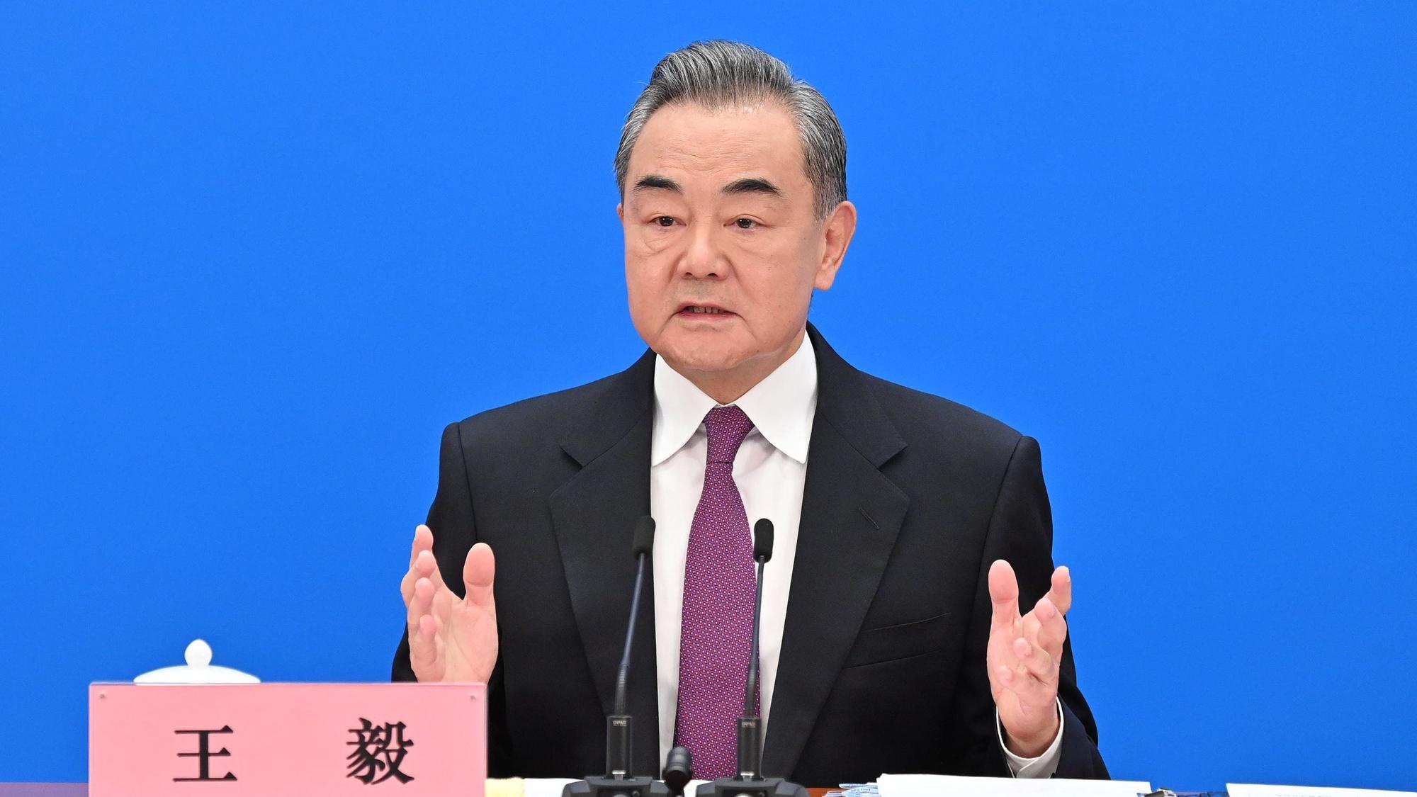 Chinas Außenminister Wang Yi sitzt vor zwei kleinen Mikrofonen und spricht.