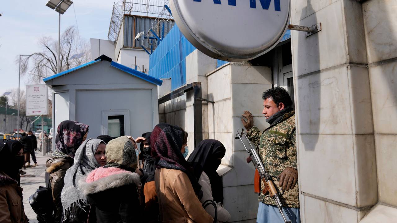 Ein afghanischer Sicherheitsbeamter mit einem AK-47 Gewehr steht vor einer Gruppe Frauen, die an einem Geldautomaten anstehen.