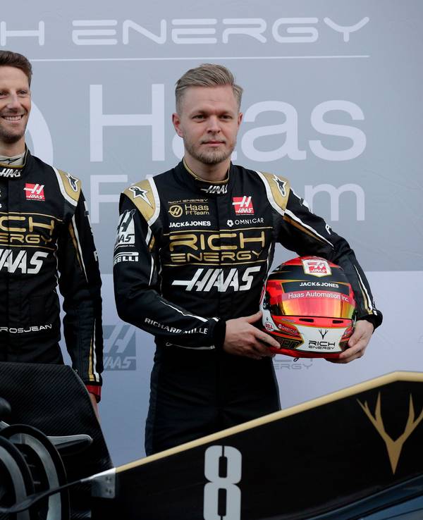 18.02.2019, Spanien, Montmelo: Die Fahrer Kevin Magnussen aus Dänemark (r) und Romain Grosjean aus Frankreich lassen sich mit dem neuen Haas F1-Auto während einer Präsentation auf der Rennstrecke Barcelona Catalunya in Montmelo, außerhalb von Barcelona fotografieren.