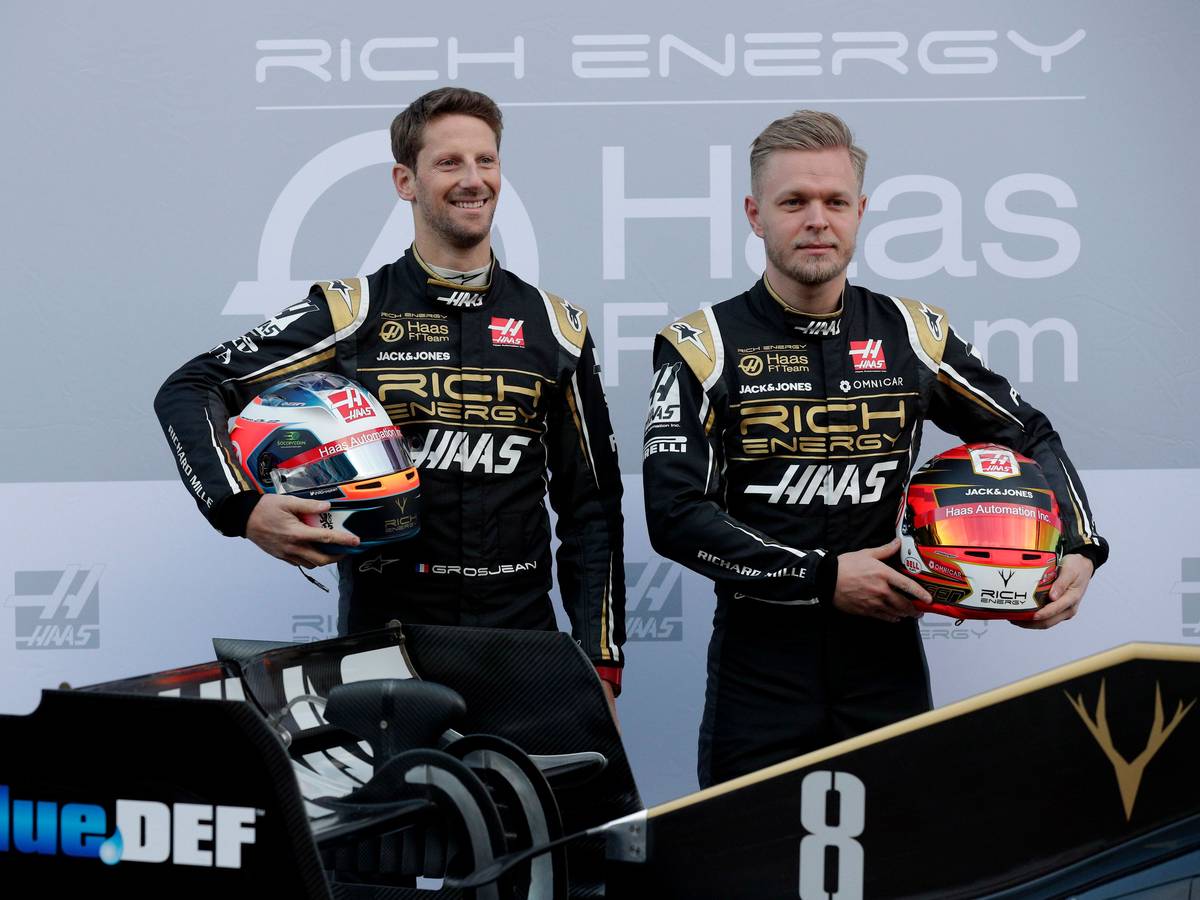 18.02.2019, Spanien, Montmelo: Die Fahrer Kevin Magnussen aus Dänemark (r) und Romain Grosjean aus Frankreich lassen sich mit dem neuen Haas F1-Auto während einer Präsentation auf der Rennstrecke Barcelona Catalunya in Montmelo, außerhalb von Barcelona fotografieren.
