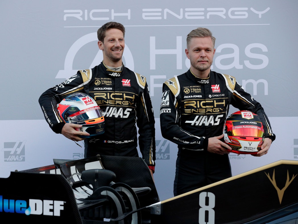 18.02.2019, Spanien, Montmelo: Die Fahrer Kevin Magnussen aus Dänemark (r) und Romain Grosjean aus Frankreich lassen sich mit dem neuen Haas F1-Auto während einer Präsentation auf der Rennstrecke Barcelona Catalunya in Montmelo, außerhalb von Barcelona fotografieren.