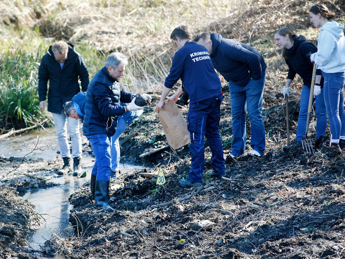 Kriminaltechniker der Polizei bei der Arbeit an einem Bach.