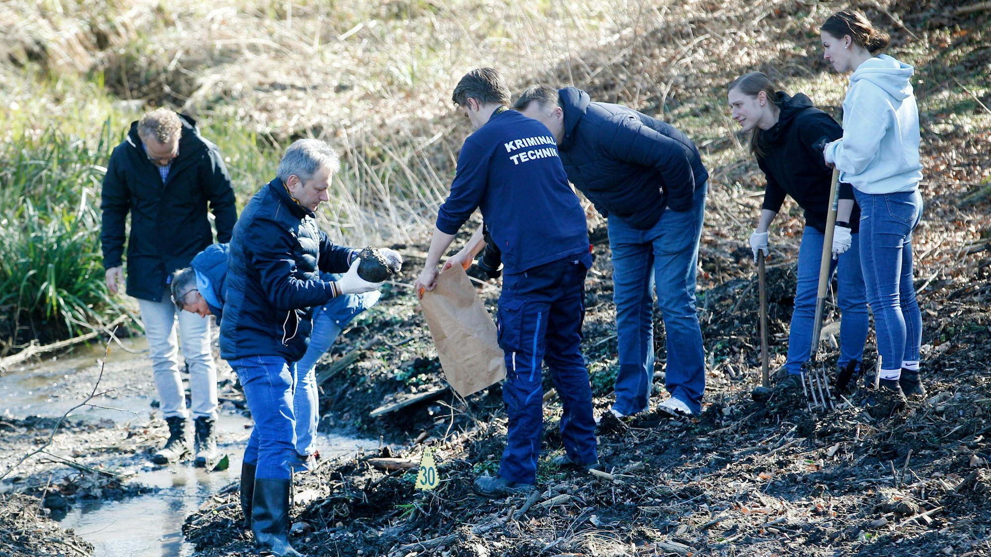 Kriminaltechniker der Polizei bei der Arbeit an einem Bach.