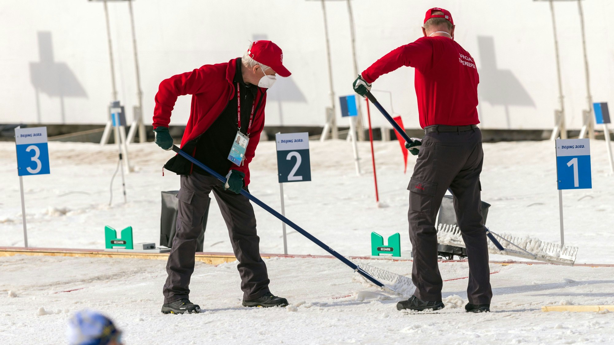 Helfer präparieren bei den Paralympics die Schneefläche am Schießstand im Biathlonstadion.