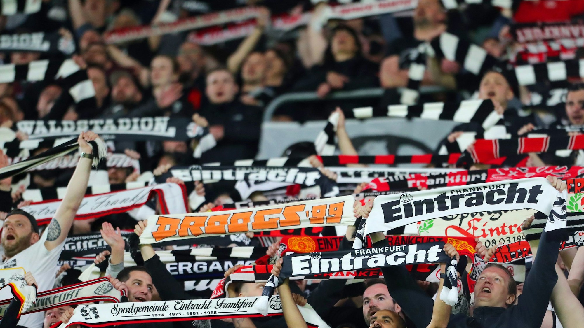 Frankfurt-Fans halten ihre Schals in die Luft.