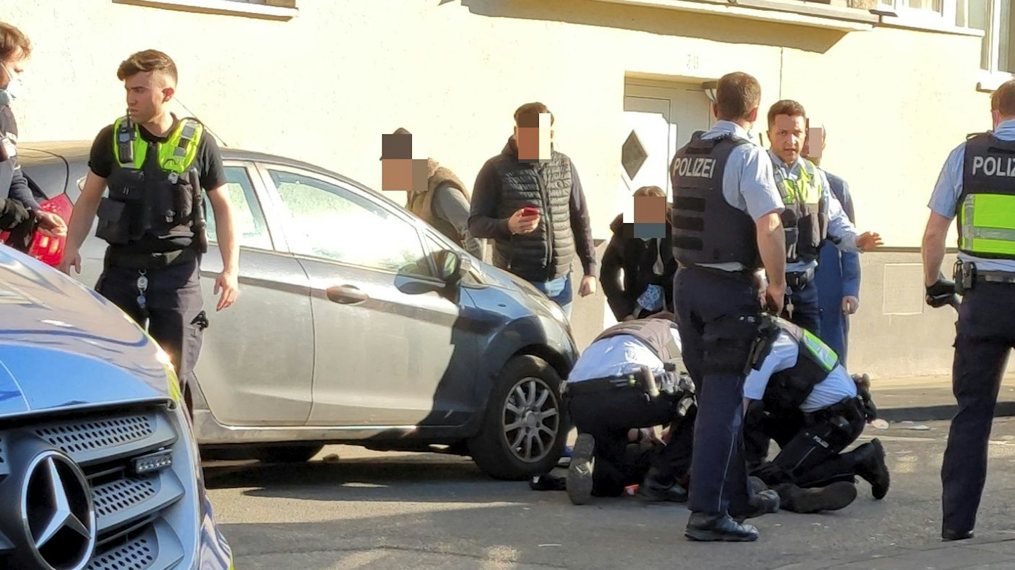 Einsatzkräfte der Polizei kümmern sich um einen Verletzten, der auf der Straße liegt.