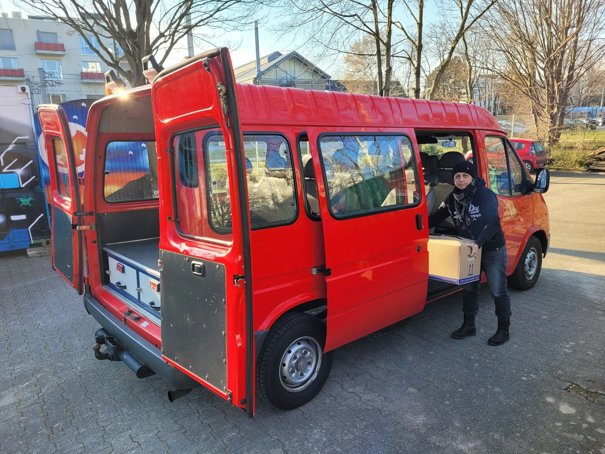 Eine Frau packt eine Kiste in einen Transporter.