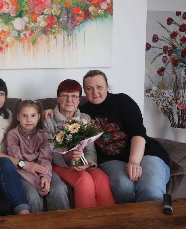 Eine ukrainische Familie sitzt auf einem Sessel und schaut in die Kamera.