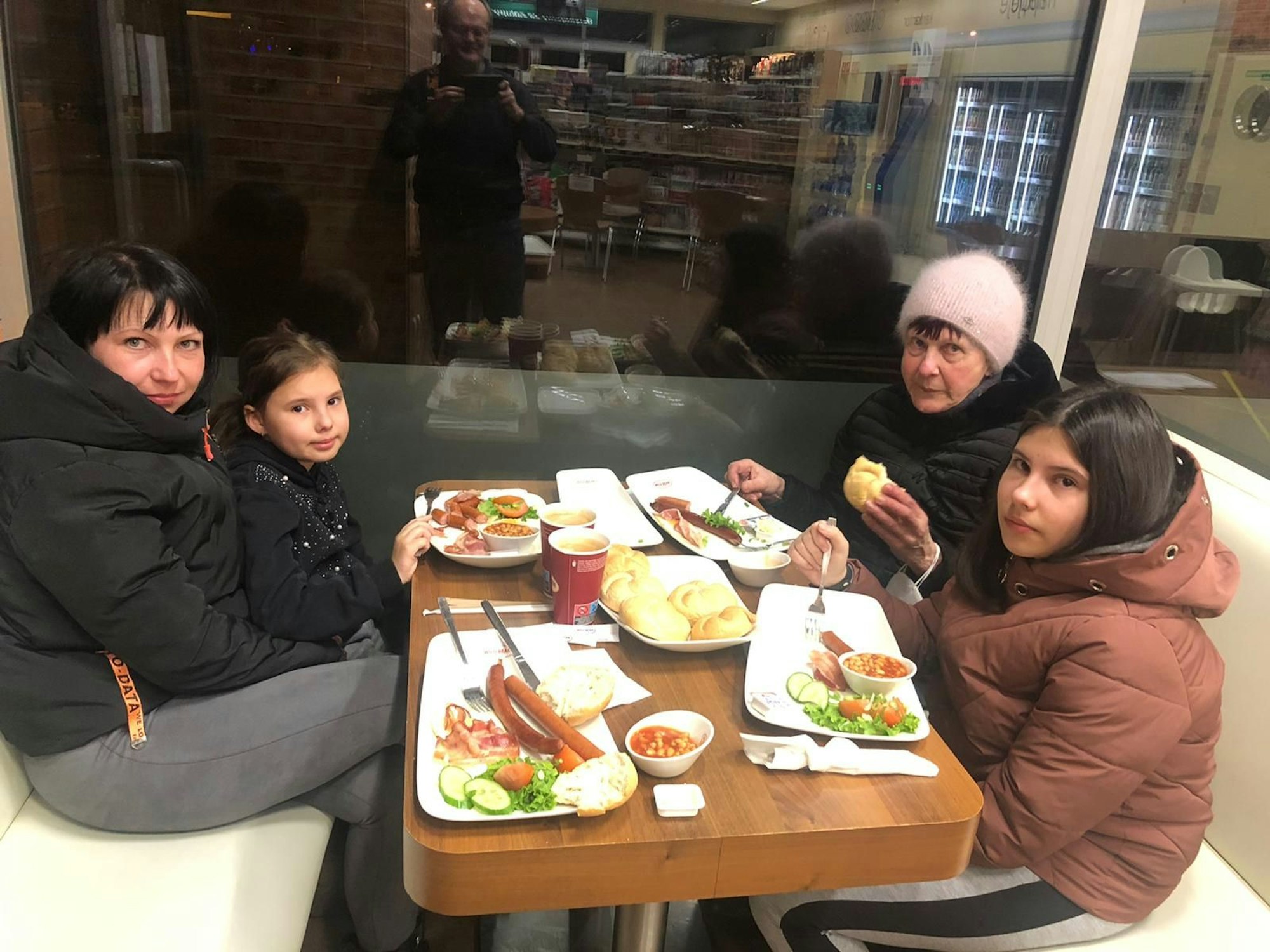 Zwei Frauen und zwei Mädchen sitzen an einem Tisch beim Essen.