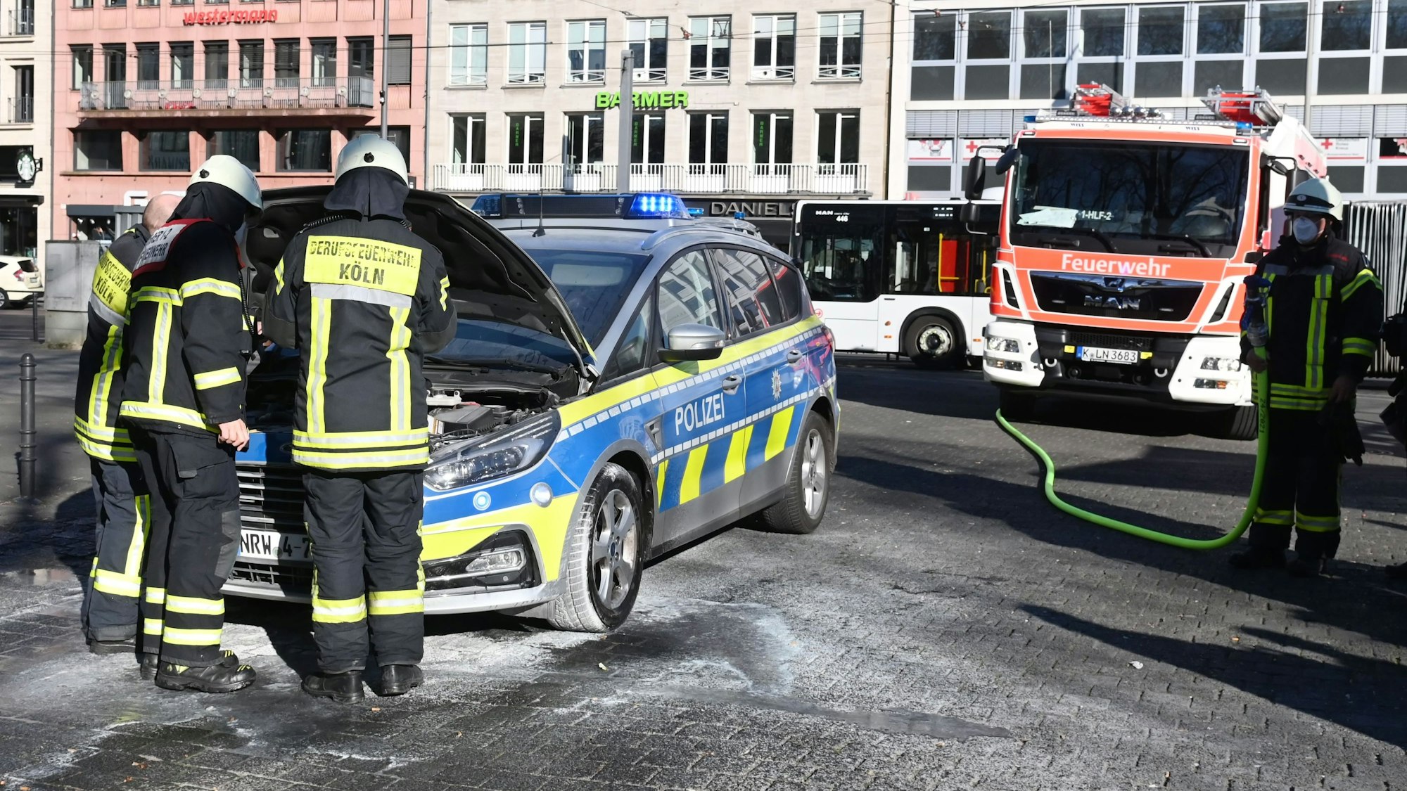 Feuerwehrmänner haben die Motorhaube eines Streifenwagens geöffnet.