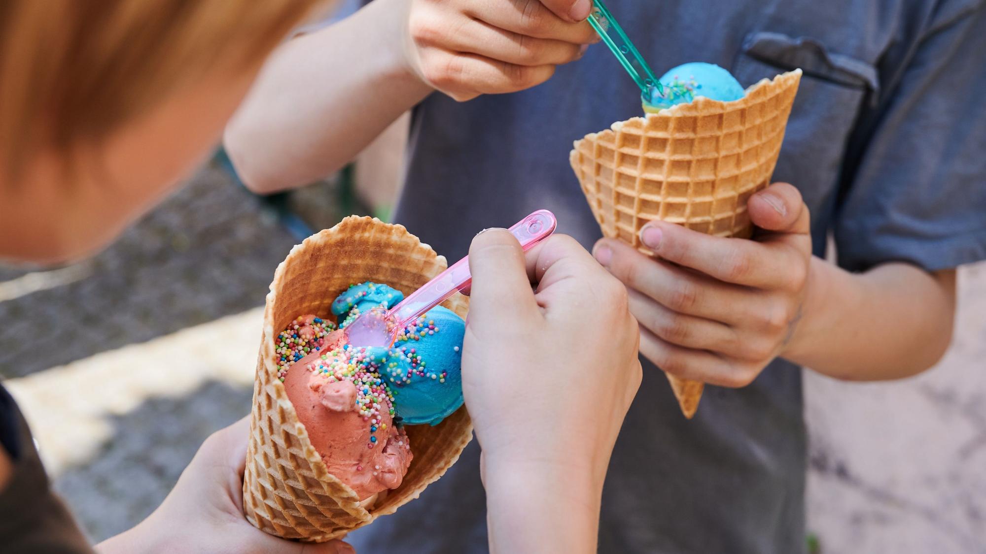Kinder essen bunte Kugeln Eis mit unterschiedlichen Geschmacksrichtungen.