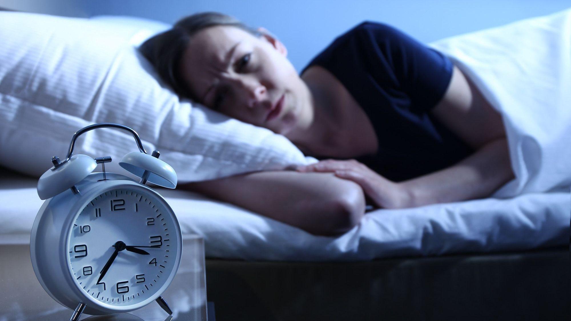 Eine Frau liegt mit Einschlafproblemen im Bett.