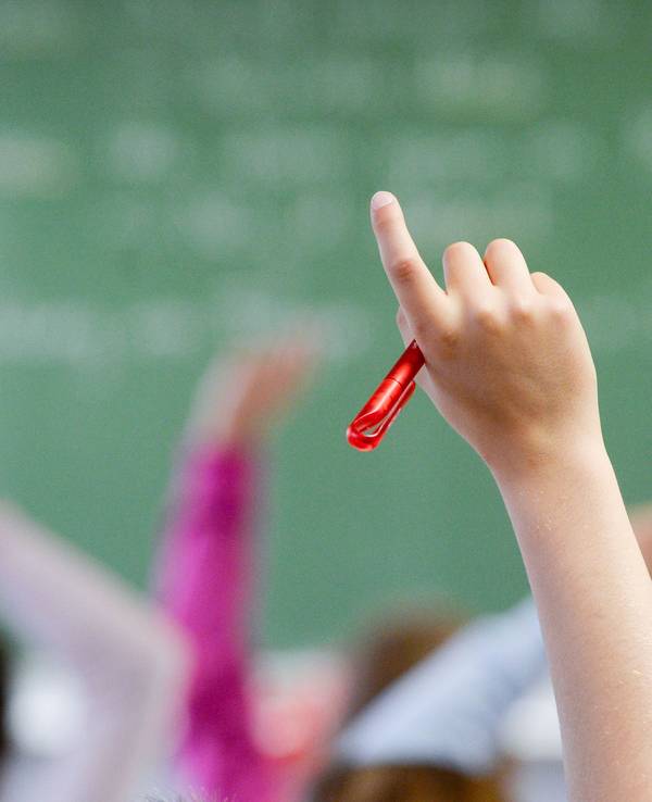 Eine Schülerin meldet sich in einem Klassenzimmer.