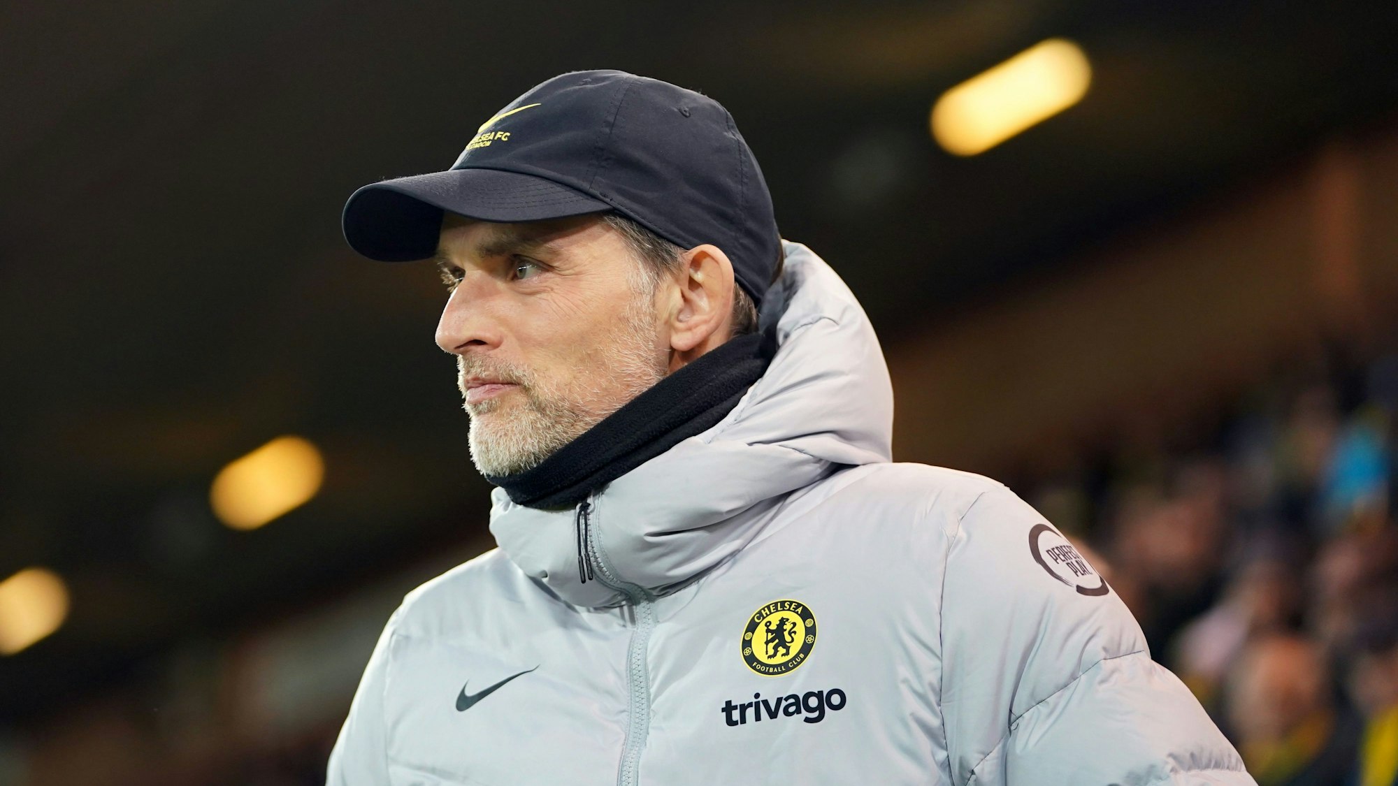 Thomas Tuchel steht in Jacke am Spielfeldrand und trägt zusätzlich eine Kappe.